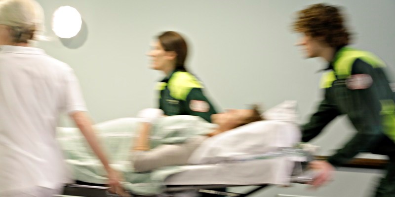 Personal inom akutsjukvården springer med patient som ligger i en säng