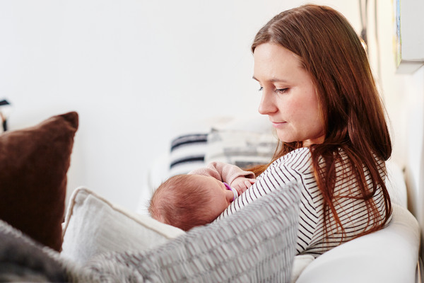 Nybliven mamma med bebis i soffa